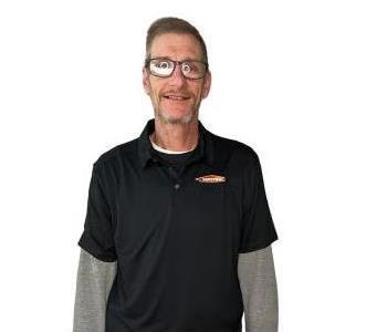 male employee smiling in front of a white wall background