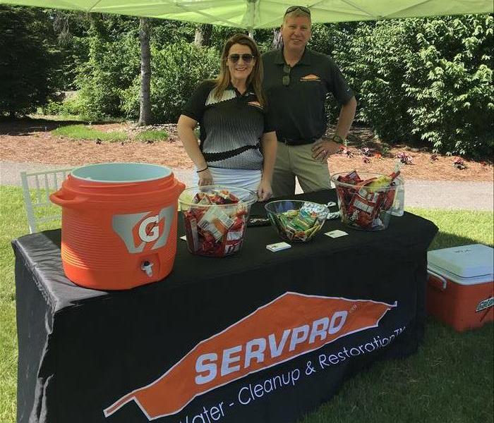 female and male employee standing behind table at golf outing