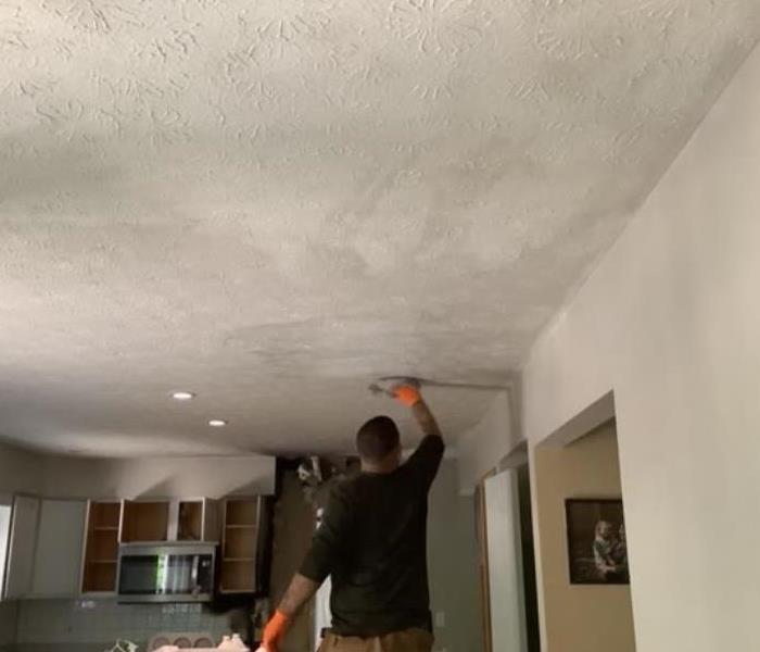 employee cleaning ceiling after fire